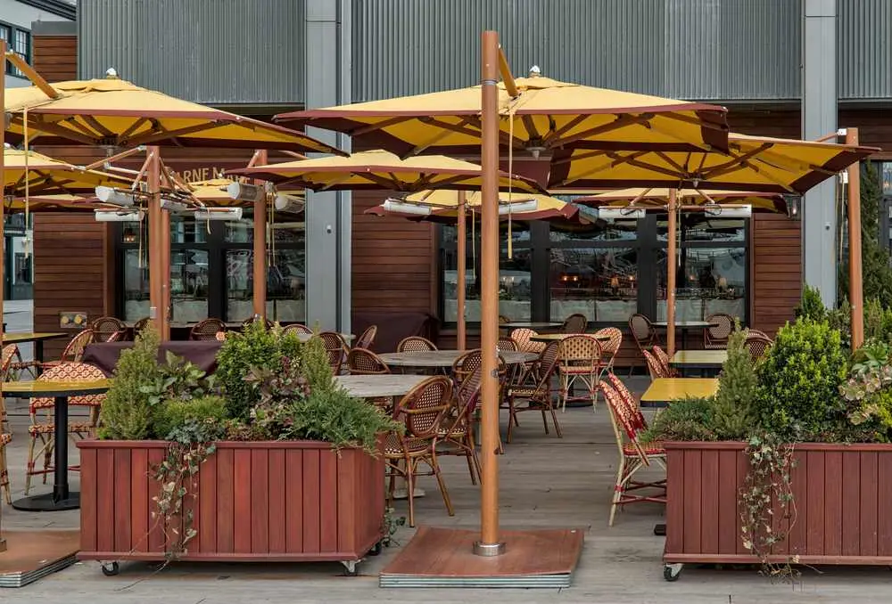 outdoor dining patio with plants and umbrellas to protect from the sun